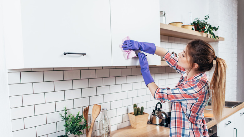 Woman cleaning kitchen cabinet