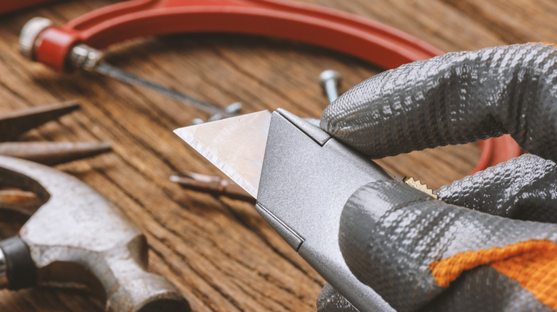 Hand holding a metal retractable knife