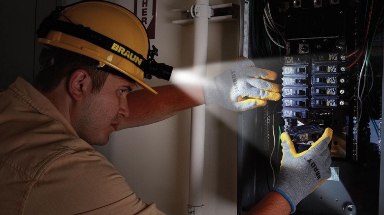 Person wearing a headlamp while fixing a fuse box