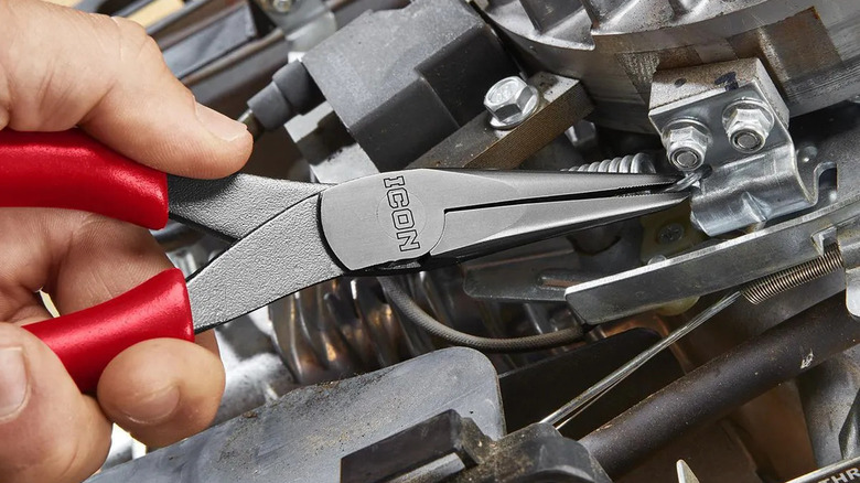 Hand using needle nose pliers to adjust a wire