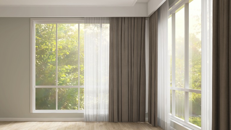 Empty room with gray wall, brown blackout and white sheer curtain.