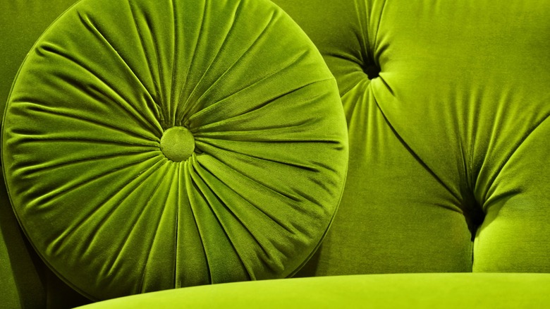 Green velvet couch with round pillow