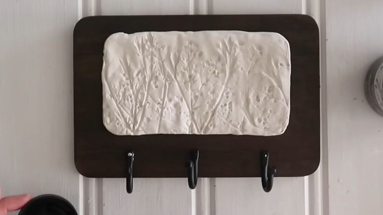 A decorative coffee mug hanger with three hooks.