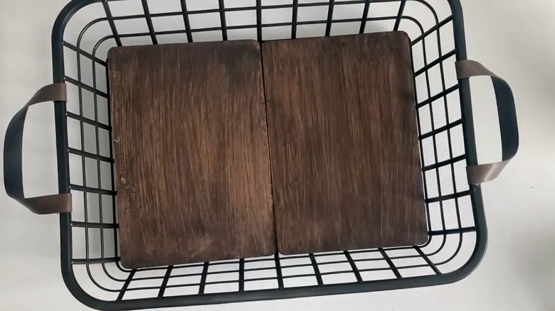 A large toiletries basket with a wooden base and leather handles.