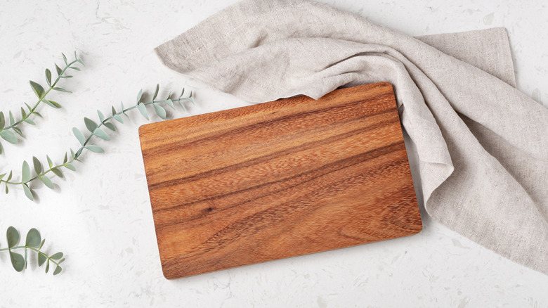 A wooden cutting on a marble background with a kitchen towel.