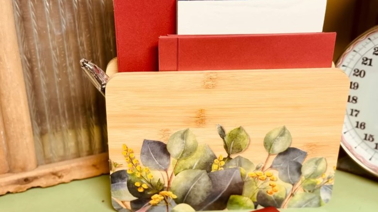 A wooden mail holder with a floral decal attached to the front.