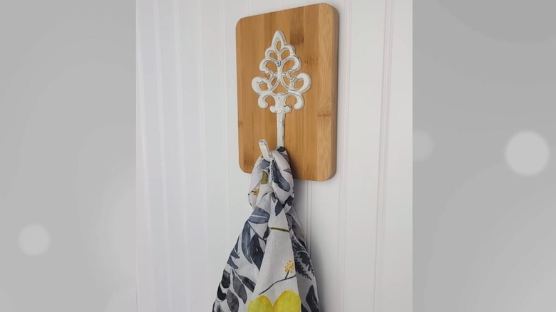 A wall hook with a wooden frame holding a towel.