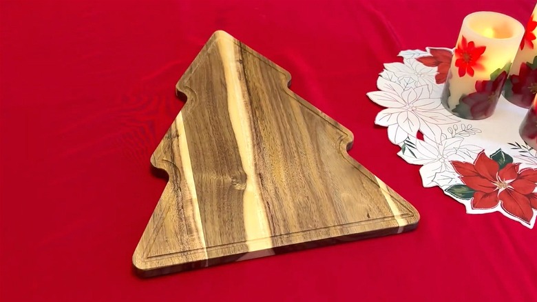 A tree-shaped cutting board rests atop a table covered with red tablecloth.