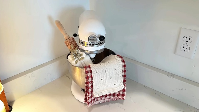 Tea towel and washcloth draped over KitchenAid cooking robot.
