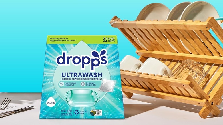 A box of Dropps UltraWash Dishwasher Pods sits next to a bamboo dish-drying rack