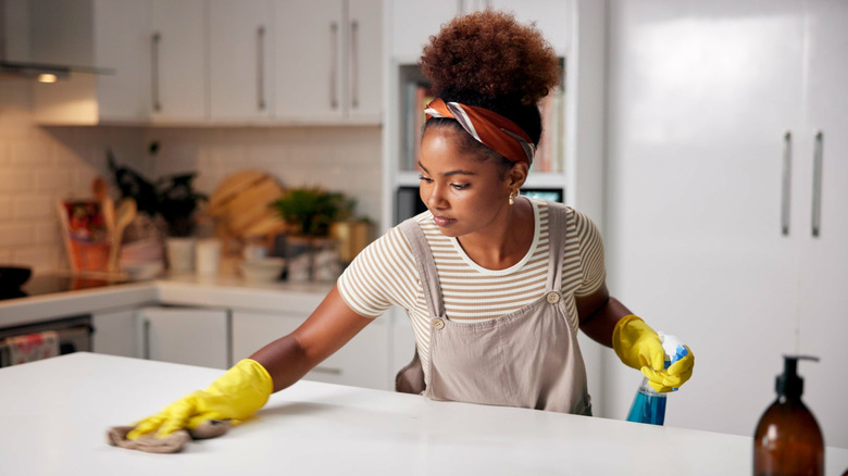 A young woman wipes a kitchen countertop