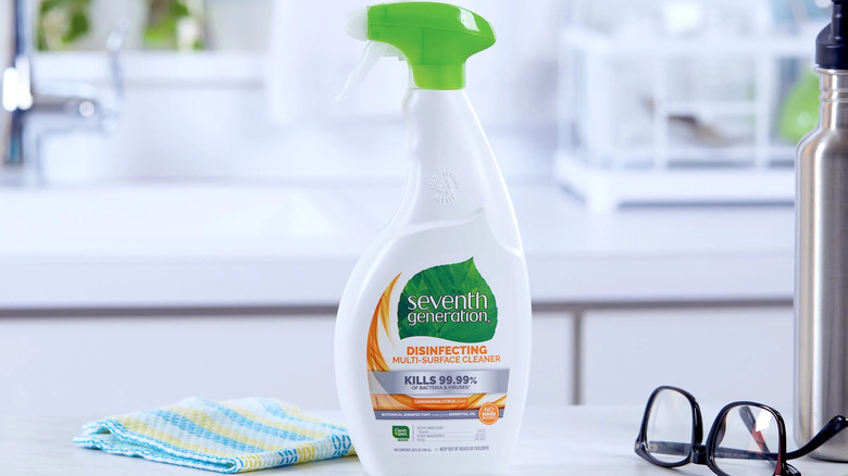 A pair of glasses and a dishrag sit next to a bottle of Seventh Generation Disinfecting Multi-Surface Cleaner