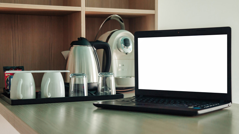 A coffee maker and kettle beside a laptop