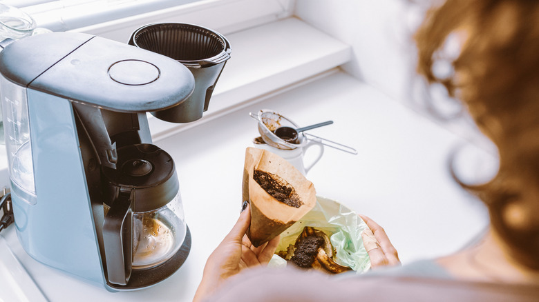 Woman emptying coffee filter while cleaning coffee maker