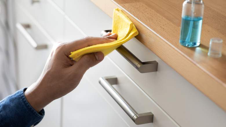 Person cleaning kitchen drawer pulls