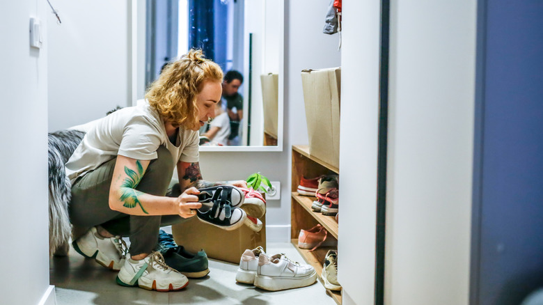 Person kneeling while organizing shoes on rack
