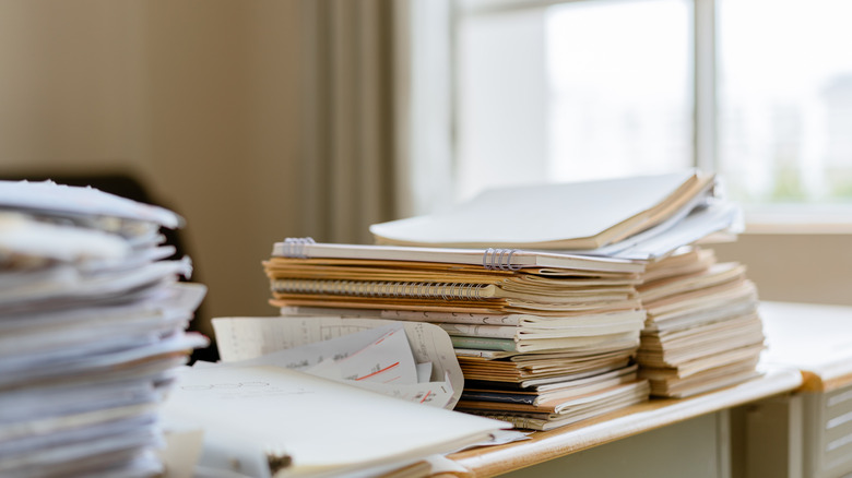 Piles of papers and notebooks on office desk