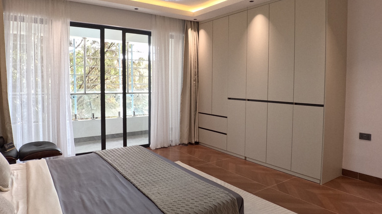 Bedroom with large balcony window and modern cabinet wardrobe in corner.