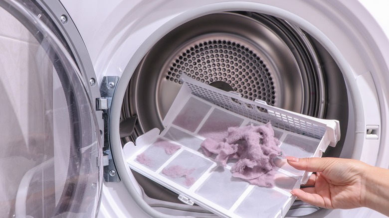 Hand taking lint out of a dryer