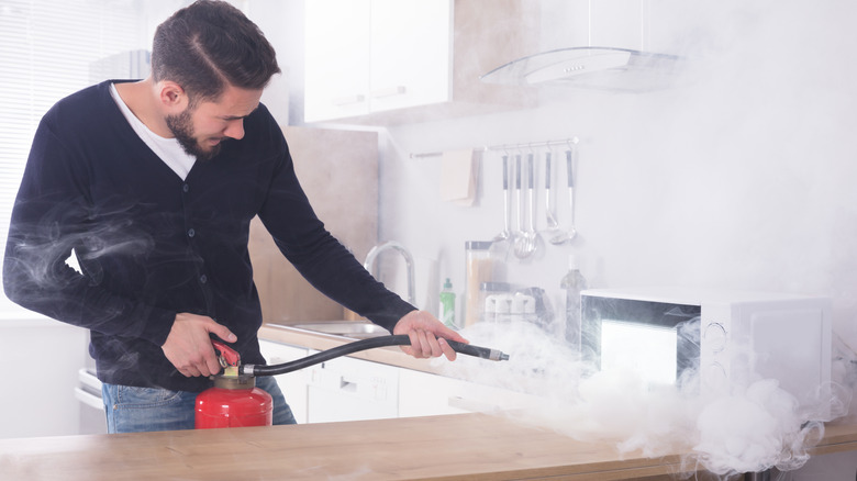 A man extinguishing a microwave fire in a kitchen.