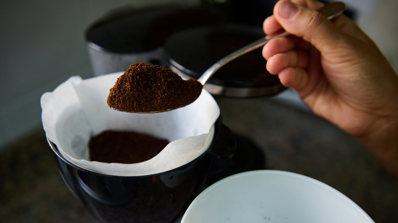 Closeup of hand scooping coffee grounds