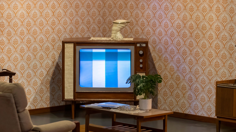 Closeup of an old TV in the corner of a wallpapered room