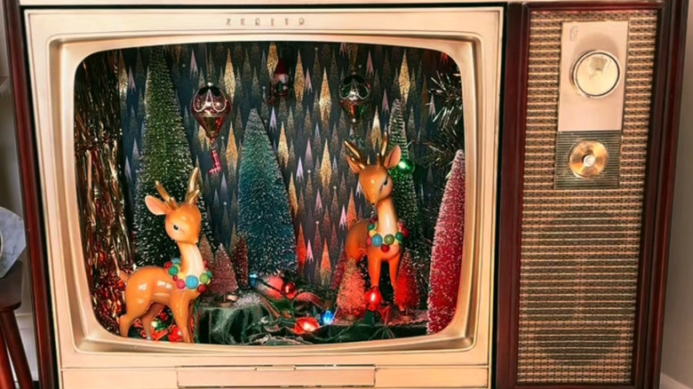 Closeup of a vintage TV turned into a seasonal decor display with retro-styled deer, bottle trees and sparkly diamond wallpaper background
