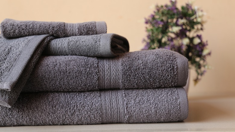 Stack of gray towels on a table in front of flowers