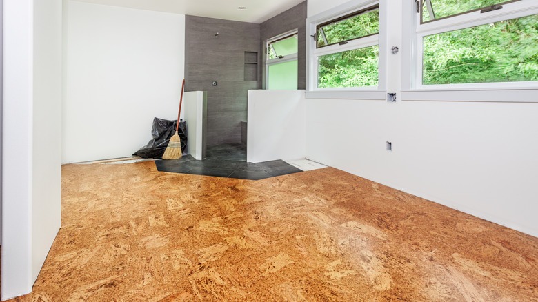 cork floor in new home with broom and trash bag in a corner