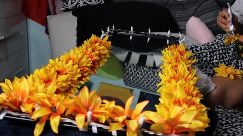 Woman adding fake yellow flowers around mirror border