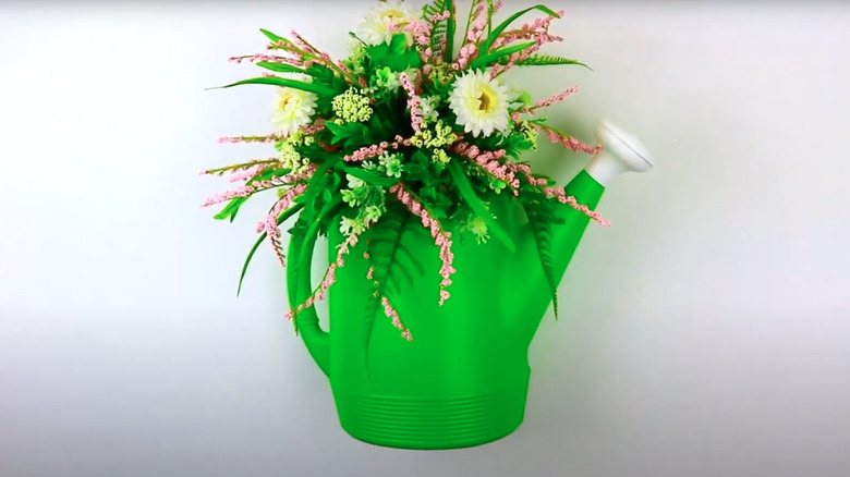 Green watering can holding bouquet of flowers