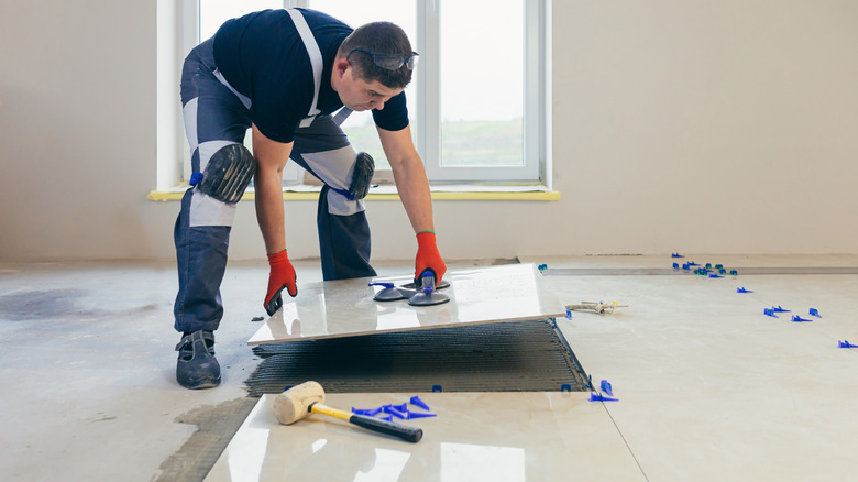 A construction worker laying large tiles