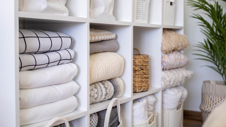 Folded linens on white shelves