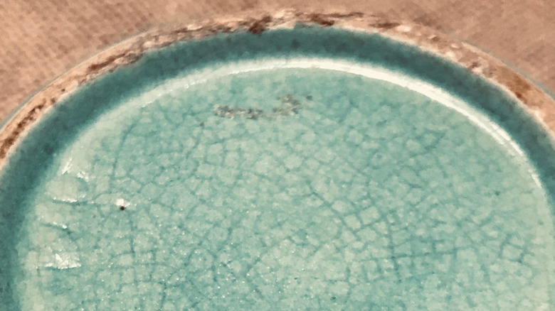 Crazing on the glaze of celadon colored piece of pottery