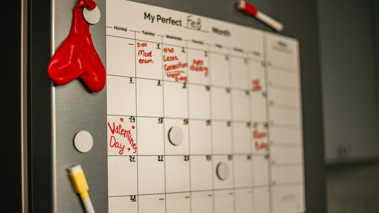 A calendar on fridge around small magnet decorations