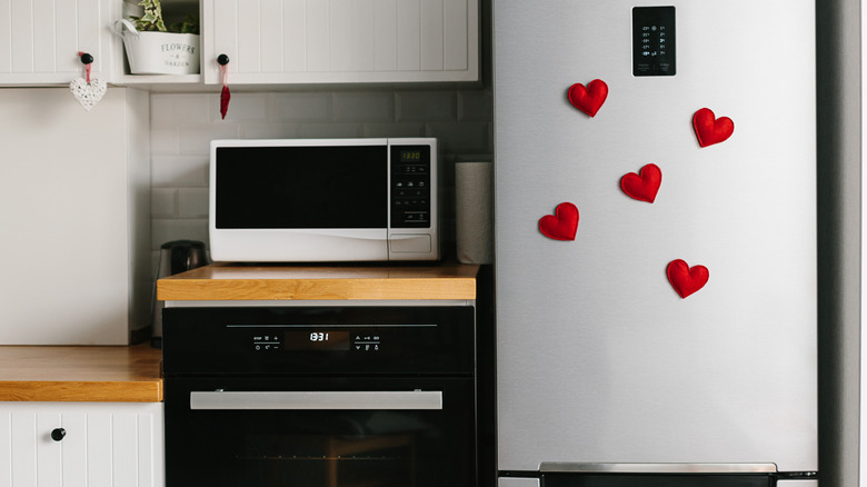 Red heart-shaped magnets on a silver fridge in kitchen