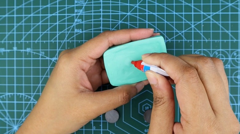 Applying glue to the back of a clay craft