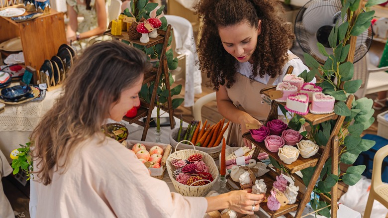 Women at a craft fair discussing items vendor is selling