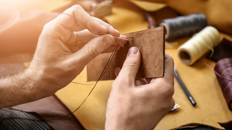 A person handcrafting a piece out of leather with needle and thread