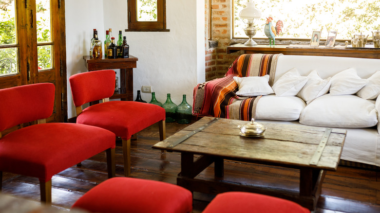 Antique farmhouse coffee table surrounded by red chairs and couch