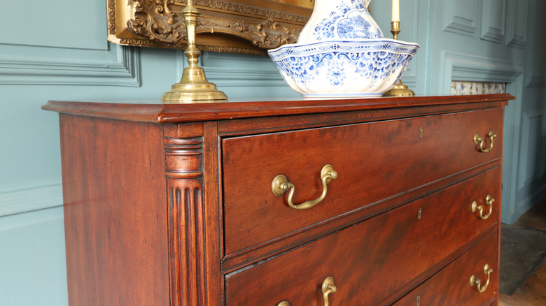 An antique wood dresser with gold hardware