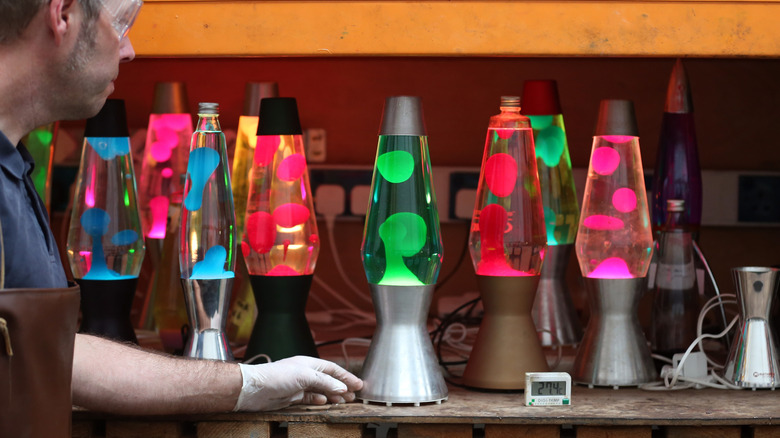 A person admiring lava lamps on a shelf