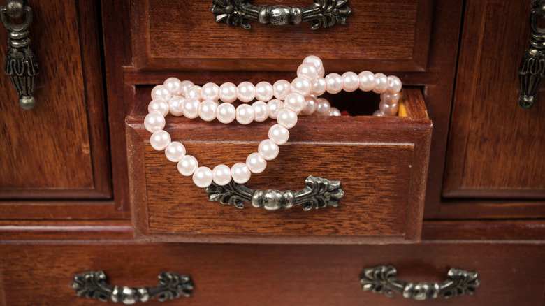 A close up of pearls in a vintage jewelry box drawer