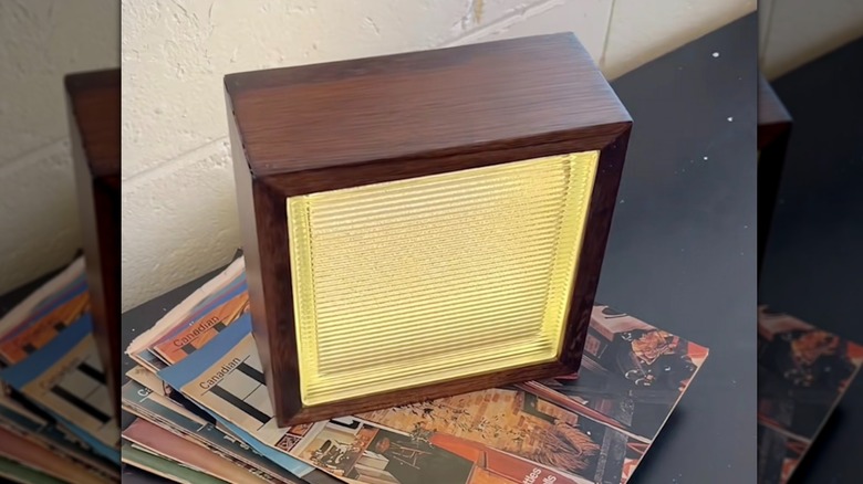 Lamp made with glass block sitting on shelf in living room.