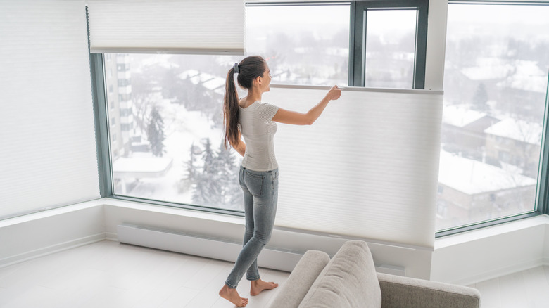 woman lowering the blinds on one window
