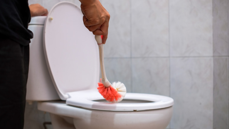 Man cleaning toilet bowl with toilet brush