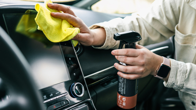 Woman spraying and cleaning car interior and wiping with rag