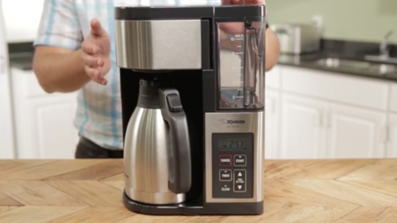 Person demonstrating Zojirushi 10-cup Coffee Maker on a counter