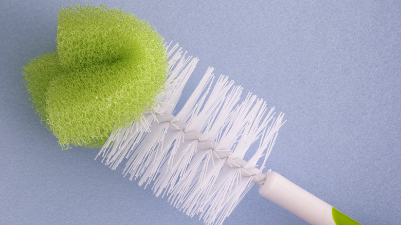A green and white bottle brush with a sponge on the end
