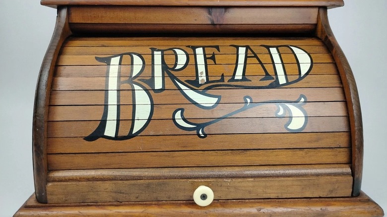 Vintage wooden roll-top breadbox with the word 'bread' painted on the front.